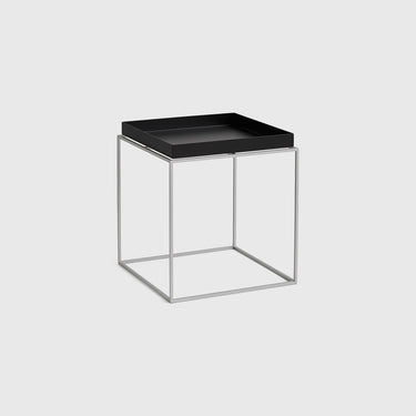 A modern square side table with a black tray top and a slim silver wire cube frame base, shown on a light gray background.