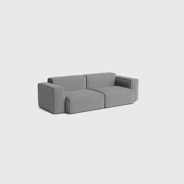 A modern modular low-profile sofa upholstered in a textured grey fabric, shown from a three-quarters angle against a light gray background.