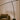 Modern black floor lamp next to a brown armchair with white curtains in the background