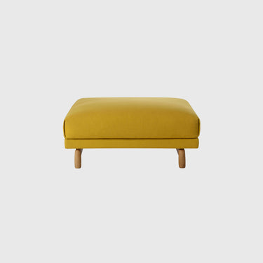 A modern rectangular ottoman with a mustard yellow textured fabric upholstery and light natural wood legs, shown against a solid light gray background.