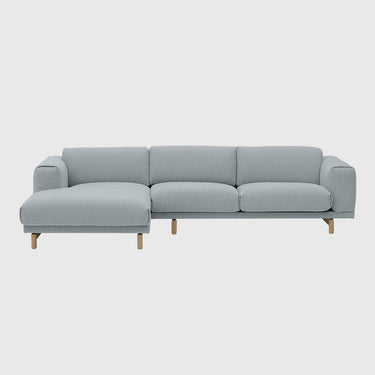 A modern three-seat sofa with a left-facing chaise lounge, upholstered in a light gray textured fabric, supported by four tapered natural wood legs, shown against a solid light gray background.