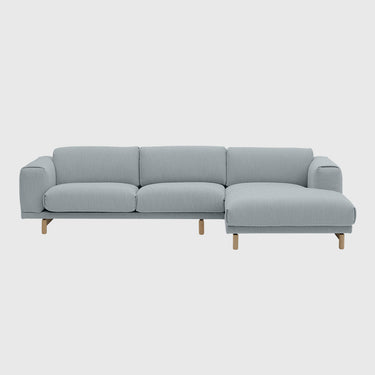 A modern three-seat sofa with a left-facing chaise lounge, upholstered in a light gray textured fabric, supported by four tapered natural wood legs, shown against a solid light grey background.