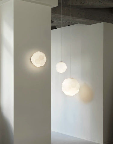 Three spherical pendant lights hanging in a minimalistic room with concrete ceiling.