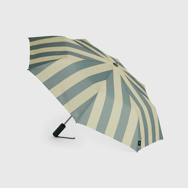A compact folding umbrella with alternating vertical stripes in sage green and cream, shown open against a light gray background.