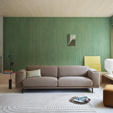 Interior image of a 3.5 seater rest sofa upholstered in taupe boucle fabric in a warmly lit room. 