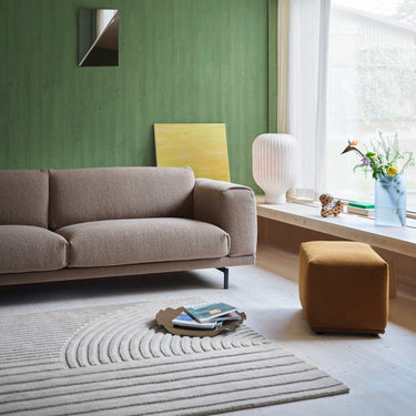 Interior image of a 3.5 seater rest sofa upholstered in taupe boucle fabric in a warmly lit room. 