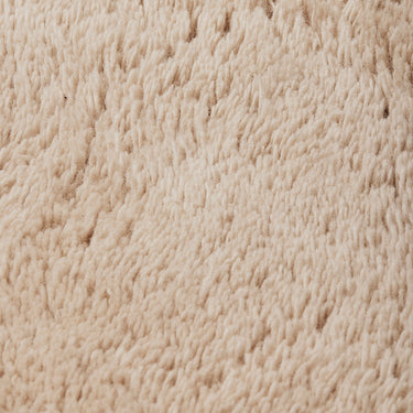 A close-up texture shot of a soft, plush beige fabric with a looped or boucle-like surface.