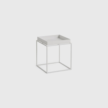 A minimalist white side table featuring a square tray top nested within an open cube metal frame, shown against a solid light gray background.