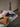 A stack of textured throw pillows in dusty pink, light gray, navy blue, mustard orange, and cream resting on a light beige upholstered bench in a modern room with a terrazzo floor.