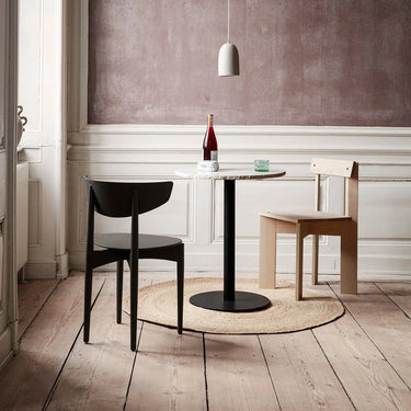 Interior image of 2 chairs and a slim table in the middle of a well lit room. 