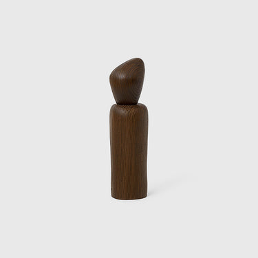 A dark brown wooden cairn grinder with a sculpted design, standing upright on a white background.