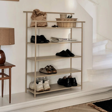 Interior image of a cashmere shelving rack with shoes on by a back door with a rug and lounge chair.