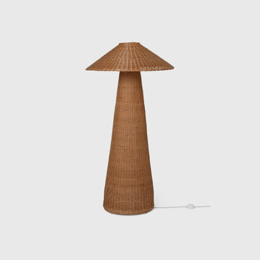 A conical rattan floor lamp with a flat, wide base and a tapered top, featuring an internal light source, with a visible power cord.