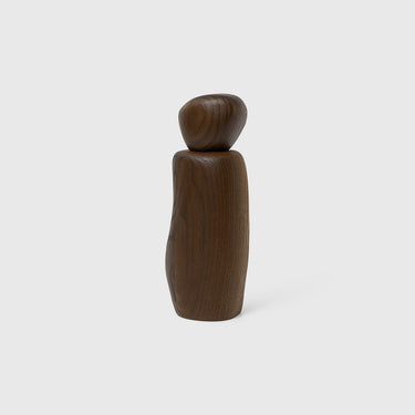 A dark brown wooden cairn grinder with a sculpted design, standing upright on a white background.