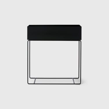 A black rectangular plant box with thin metal legs, designed for home decor and storage.